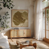 Monstera Leaf II by Wild Apple Portfolio. Shown in a natural wood frame in a cozy modern living room. Available as an archival giclee rolled canvas, fine art paper, or poster print. SKU 37204a.