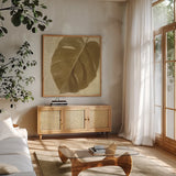 Ornate Monstera Leaf I by Wild Apple Portfolio. Shown in a natural wood frame in a cozy modern living room. Available as an archival giclee rolled canvas, fine art paper, or poster print. SKU 37203a.