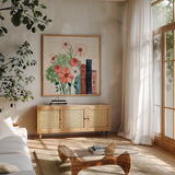 Books and Blooms I by Yvette St. Amant. Shown in a natural wood frame in a cozy modern living room. Available as an archival giclee rolled canvas, fine art paper, or poster print. SKU 97379a.