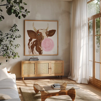 Bubblegum Cow by Yvette St. Amant. Shown in a natural wood frame in a cozy modern living room. Available as an archival giclee rolled canvas, fine art paper, or poster print. SKU 91464a.
